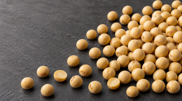 Round whole yellow field peas and thick split pea halves on a dark surface.